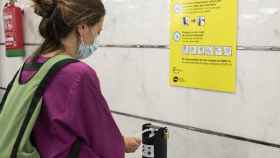 Una usuaria se pone gel hidroalcohólico en una estación de metro / TMB