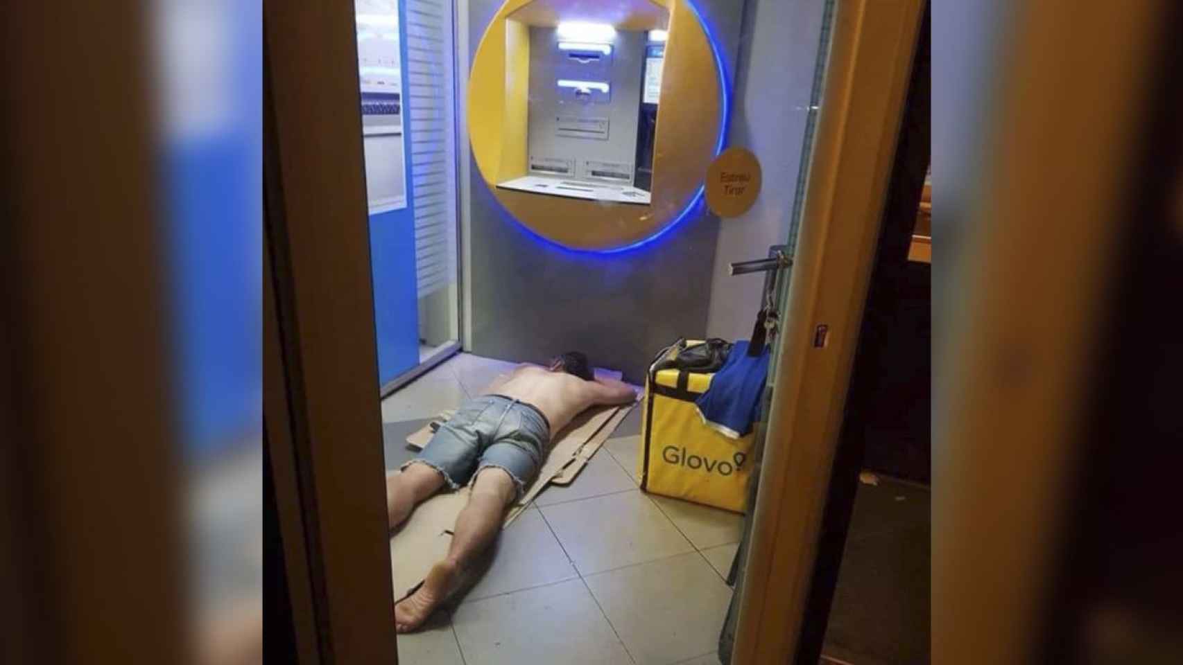 Un repartidor de Glovo durmiendo en un cajero automático