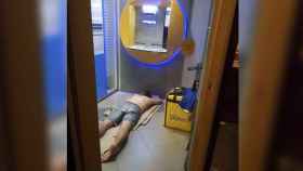 Un repartidor de Glovo durmiendo en un cajero automático
