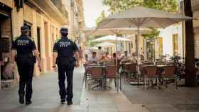 Dos guardia urbanos pasean por delante de una terraza en Barcelona / GUARDIA URBANA