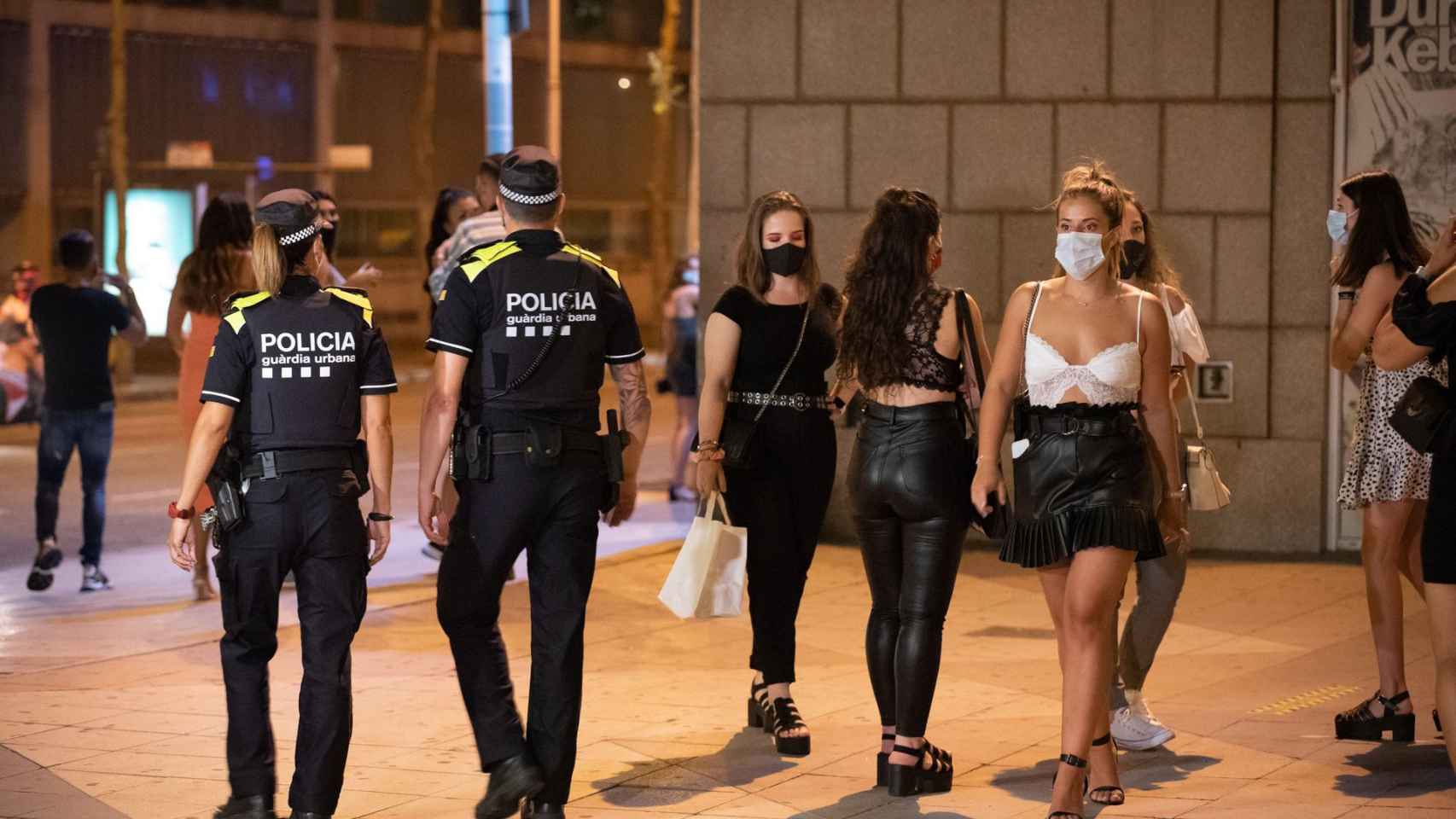 Dos agentes de la Guardia Urbana pasean entre un grupo de chicas en una zona de ocio nocturno de Barcelona / GUARDIA URBANA