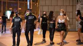 Dos agentes de la Guardia Urbana pasean entre un grupo de chicas en una zona de ocio nocturno de Barcelona / GUARDIA URBANA
