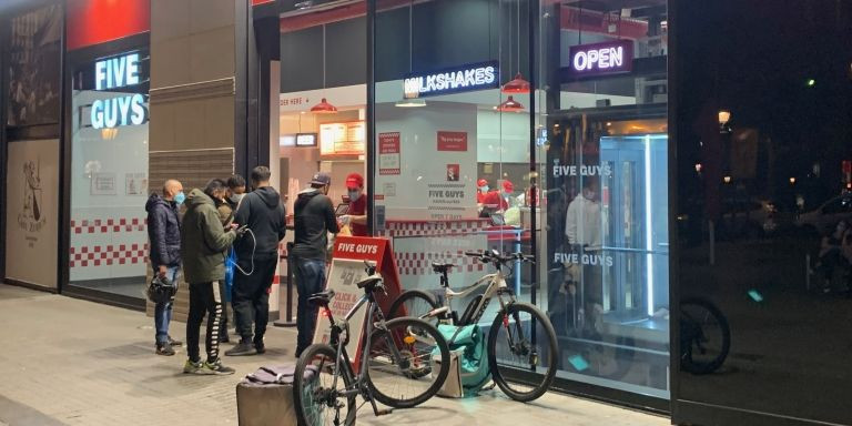 Varios 'riders' esperan enfrente de una cadena de comida rápida a los pedidos a domicilio / V.M.
