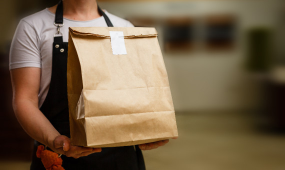 Cocinero entregando una bolsa de 'takeaway' de un restaurante / ARCHIVO