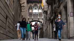 Personas caminan debajo del puente de estilo gótico del Carrer del Bisbe / PABLO MIRANZO