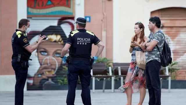 Agentes de la Guàrdia Urbana informan a dos transeúntes de la obligación de llevar mascarilla / EFE