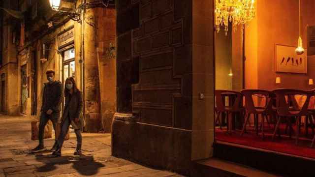 Una pareja ataviada con mascarillas pasea por el centro histórico de Barcelona, algo que no se permitirá en el toque de queda / EFE- Enric Fontcuberta