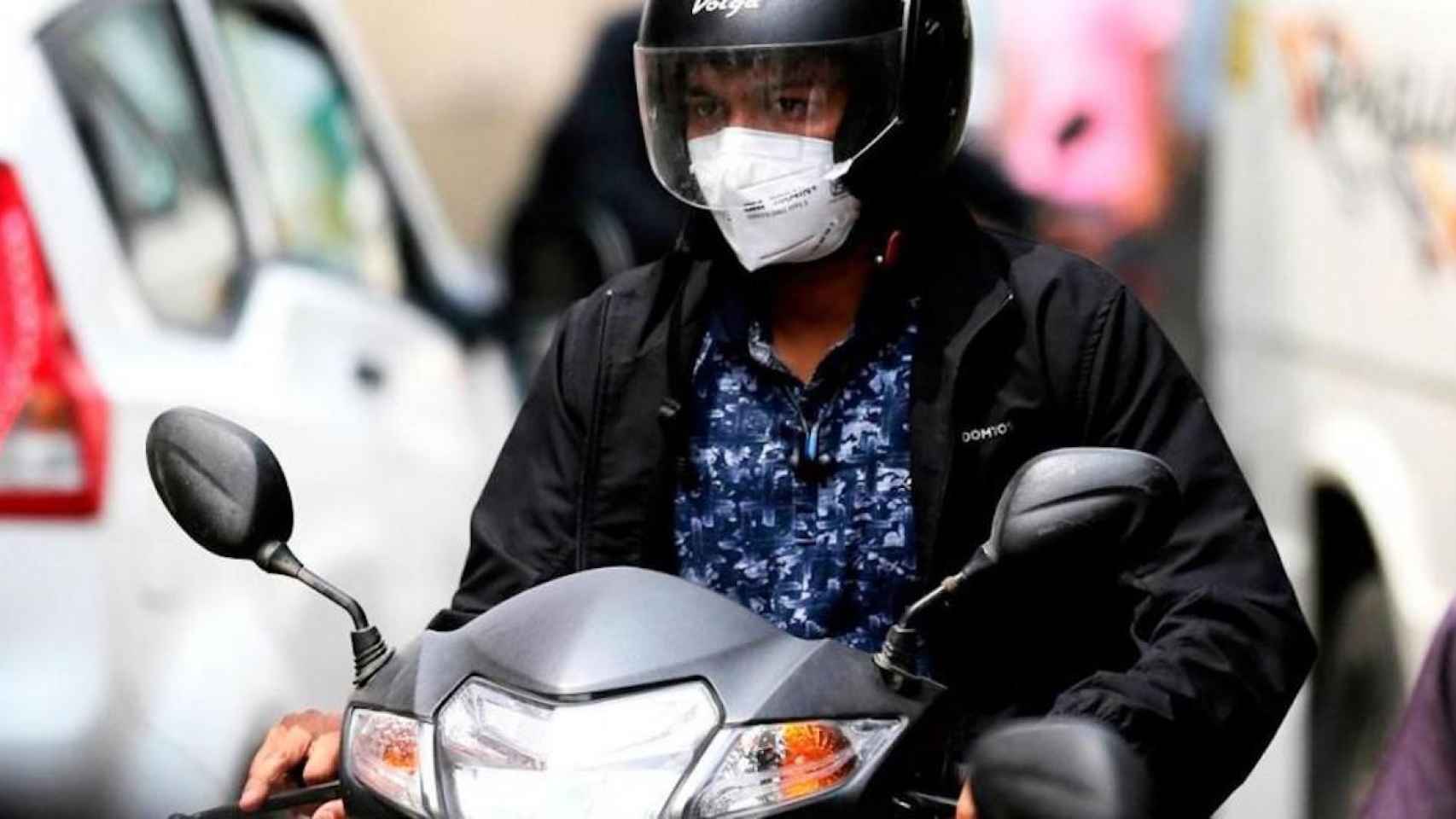 Imagen de una usuaria de moto con mascarilla protectora contra el virus / EFE