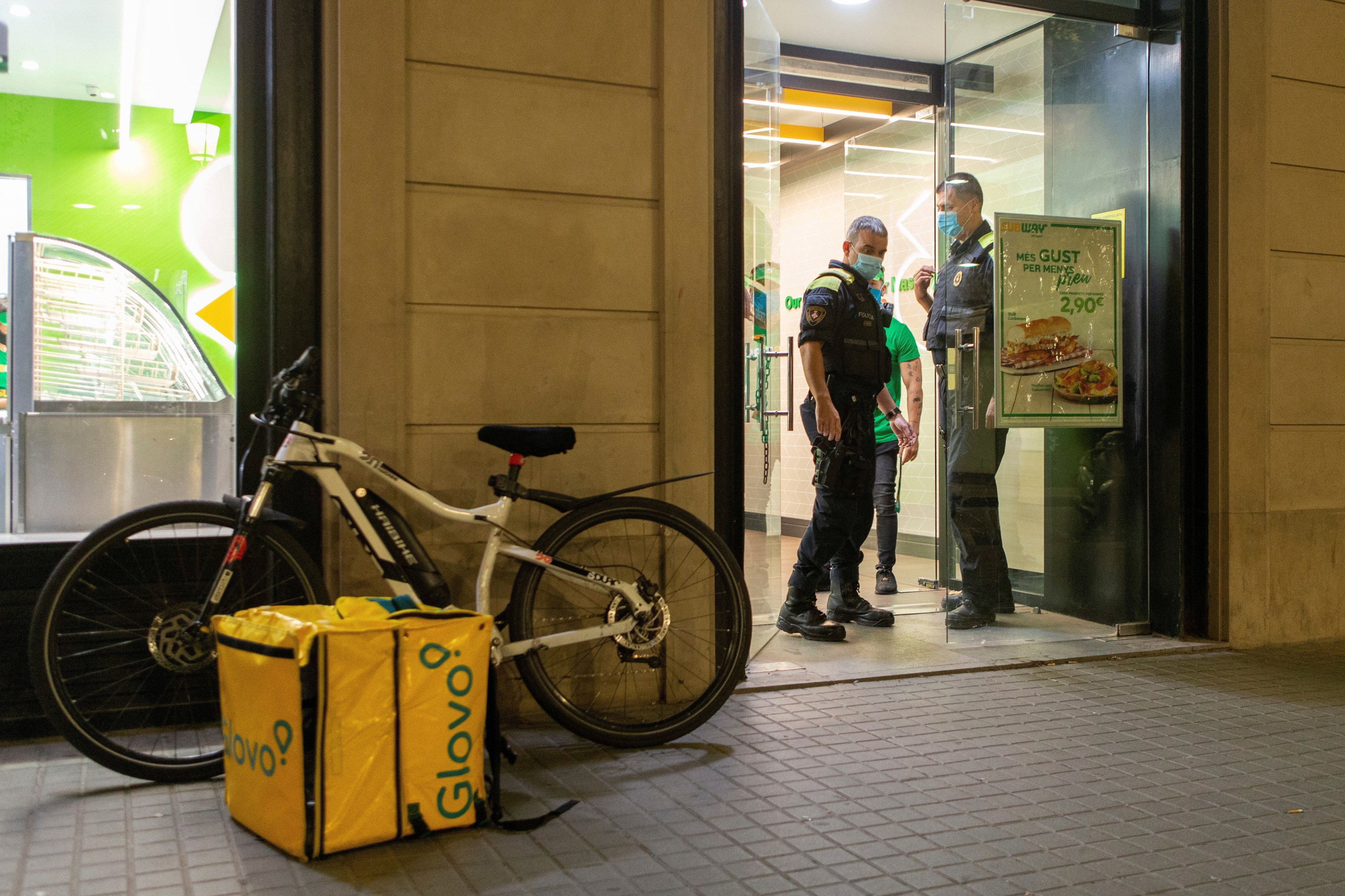 La Guardia Urbana informa del toque de queda a transeúntes, comerciantes y trabajadores de reparto de comida / EFE - Enric Fontcuberta