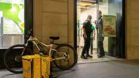 a Guardia Urbana informa del toque de queda a transeúntes, comerciantes y trabajadores de reparto de comida / EFE - Enric Fontcuberta
