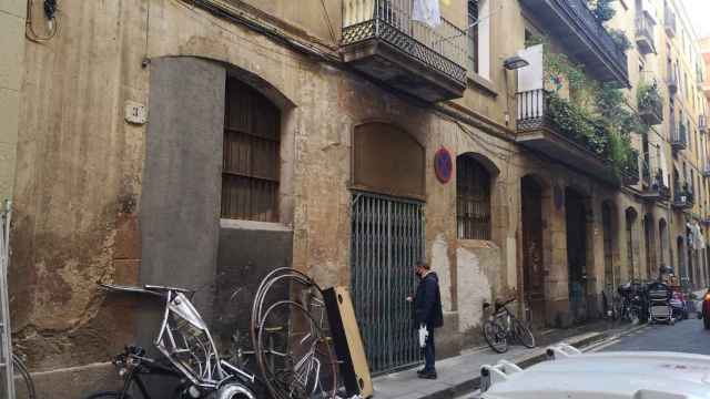 Restos de chatarra en la puerta del piso okupado en el Raval y, al fondo, los bártulos de las personas que había en el interior / G.A