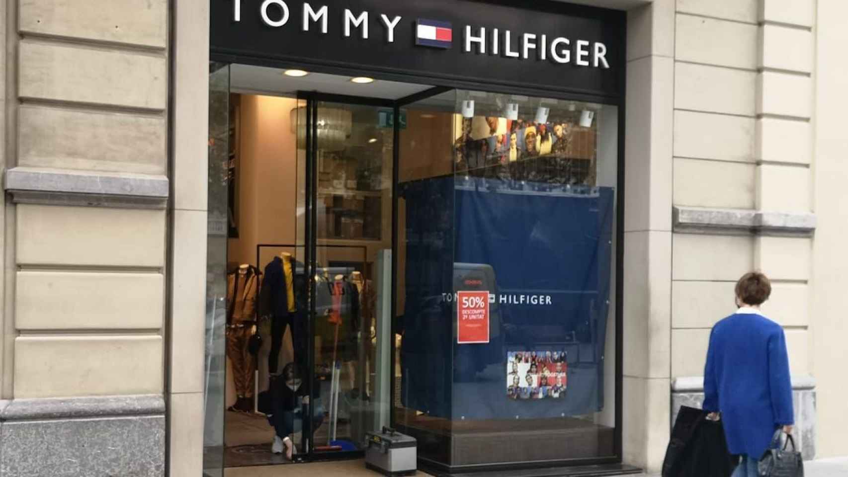 Una empleada de la tienda Tommy Hilfiger, uno de los dos comercios de lujo que han sido asaltados esta madrugada en el paseo de Gràcia, arreglando la puerta / G.A.