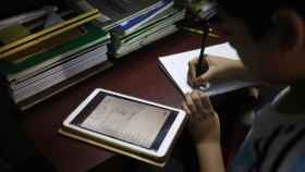 Un niño hace los deberes mientras consulta con su tableta / EFE