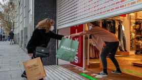 Una clienta recoge una bolsa de manos de una dependienta en un comercio del centro de Barcelona / EFE - Enric Fontcuberta