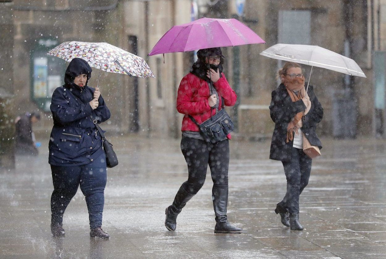 Tres personas cubiertas con un paraguas durante una jornada de lluvias en Barcelona / EFE