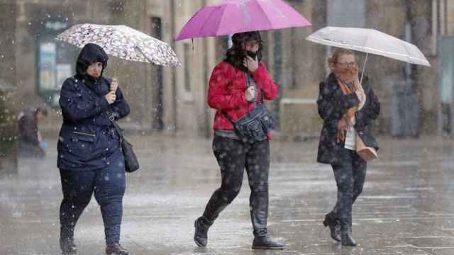 Tres personas cubiertas con un paraguas durante una jornada de lluvias en Barcelona