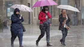Tres personas cubiertas con un paraguas durante una jornada de lluvias en Barcelona