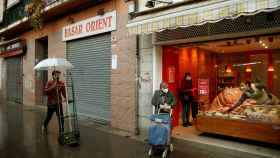 Varias personas pasan ante una tienda de alimentación del barrio de Sta Eulàlia de L'Hospitalet de Llobregat / EFE - Toni Albir