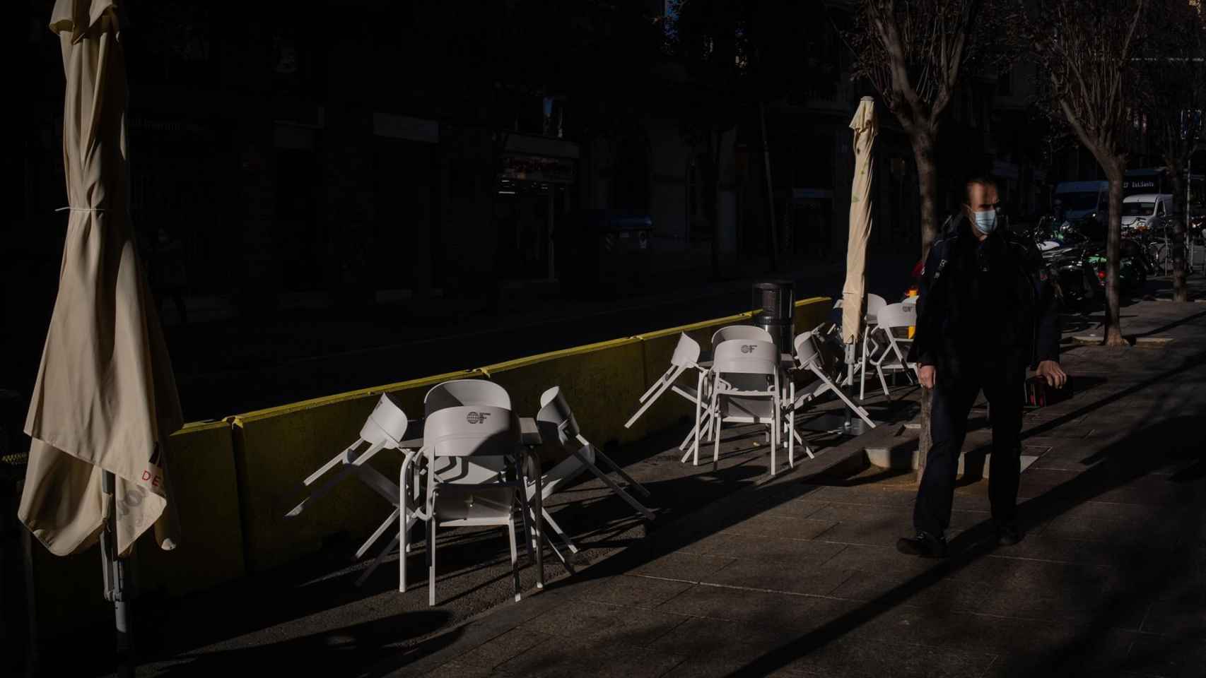 Un hombre pasa al lado de las sillas vacías de una terraza en Barcelona / EUROPA PRESS - David Zorrakino