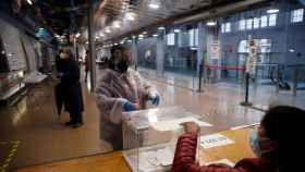 Una mujer protegida con un traje vota en el colegio electoral situado en el Mercat del Ninot en Barcelona este domingo cuando se celebran las elecciones regionales / EFE -