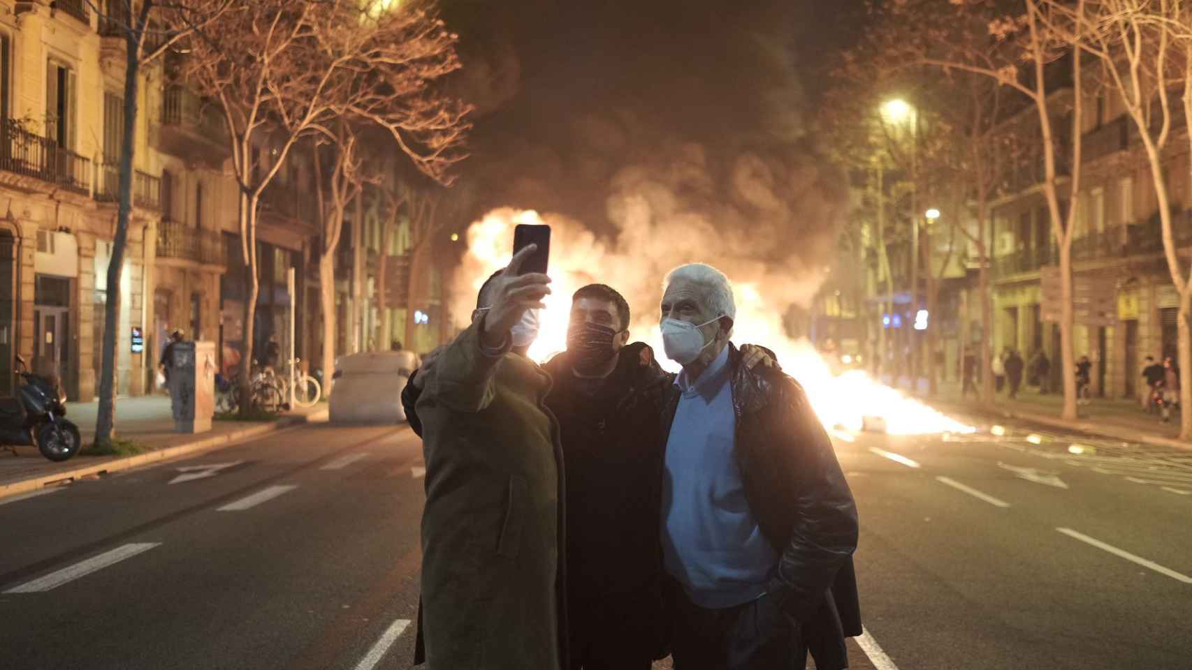 Tres hombres se hacen un 'selfie' con una barricada ardiendo de fondo durante las protestas por Hasél / PABLO MIRANZO