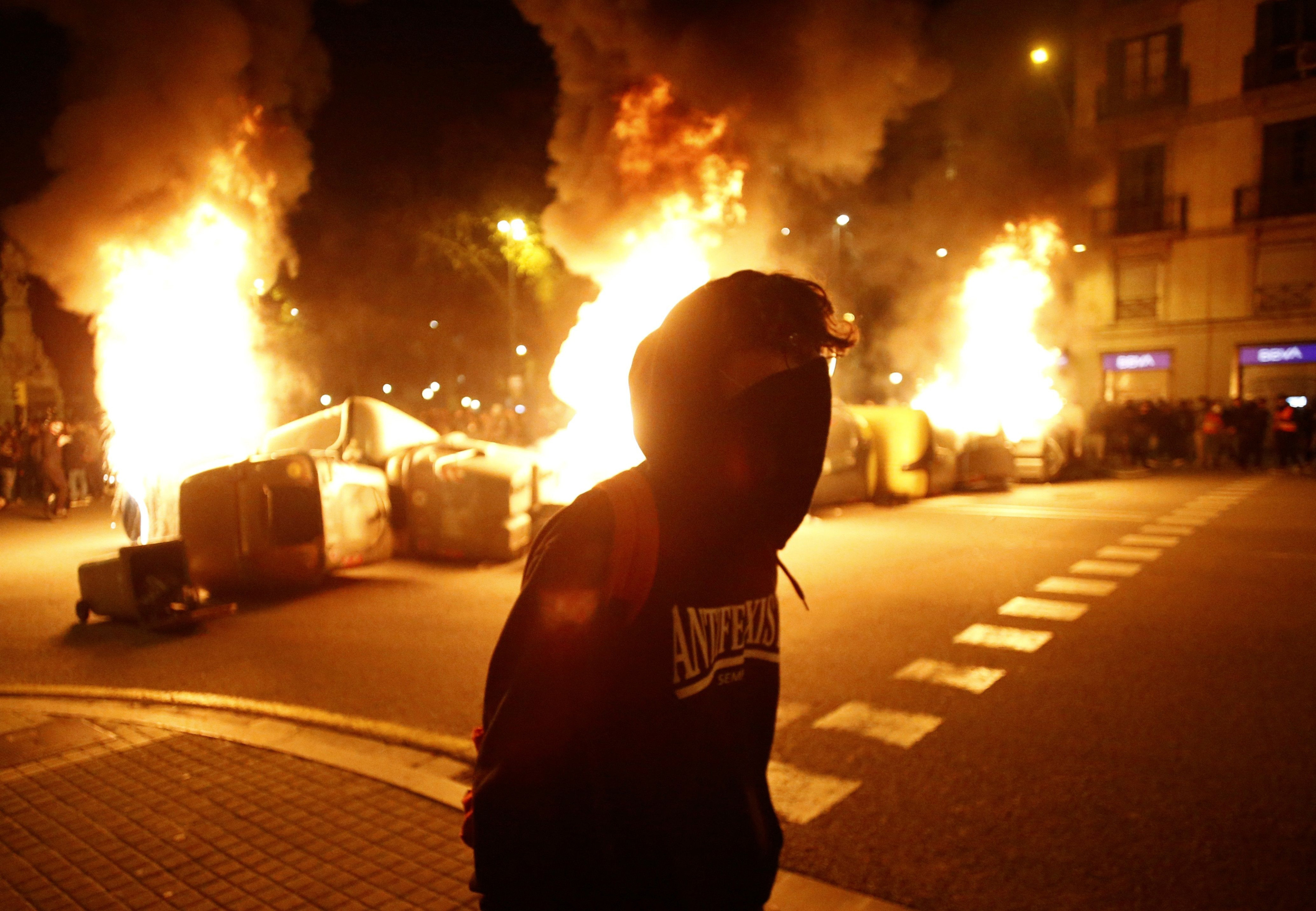 Un manifestante pasa por delante de barricadas ardiendo durante la cuarta noche de altercados por Hasél en Barcelona / EFE
