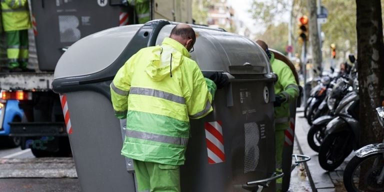 Dos operarios trasladan un contenedor en Barcelona / AJ BCN
