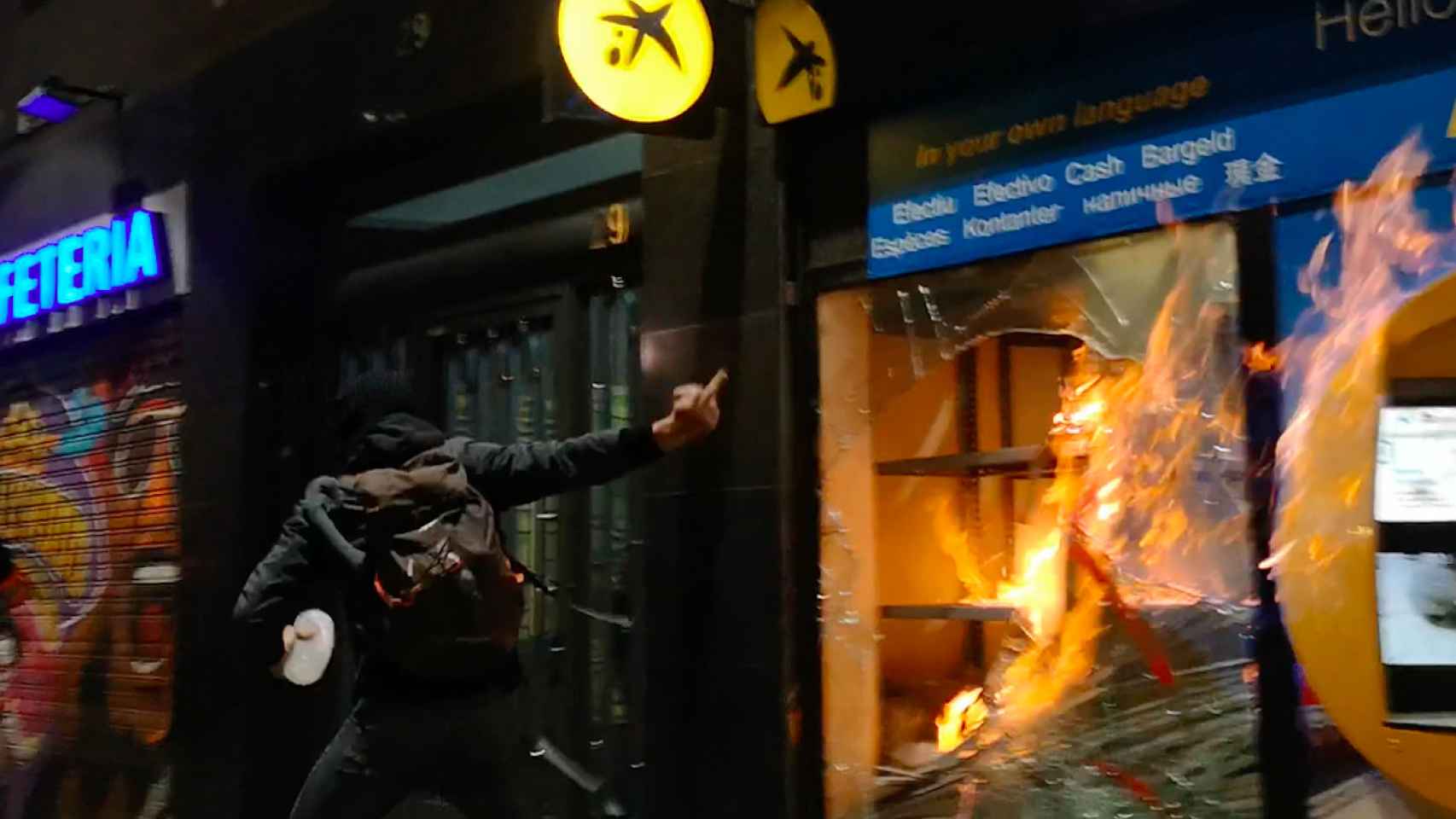 Un encapuchado prende fuego a una oficina de CaixaBank en El Raval / GUILLEM ANDRÉS