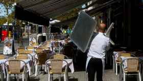 Un camarero recoge una mesa de una terraza de un restaurante del barrio de la Barceloneta / EFE - QUIQUE GARCIA