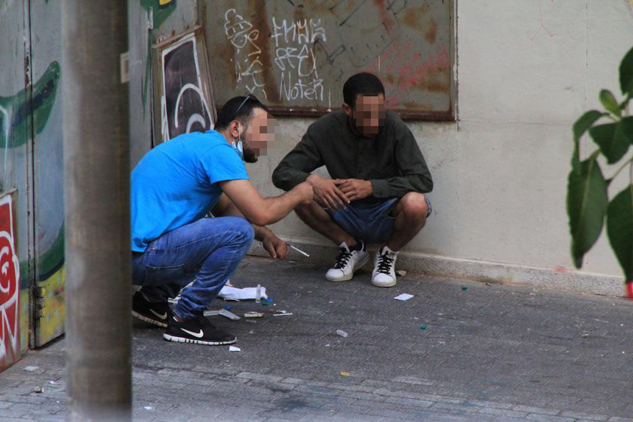 Dos usuarios de la narcosala del Raval (CAS Baluard) consumiendo heroína en el exterior del equipamiento / CEDIDA