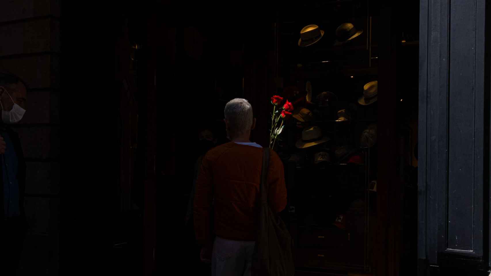Una mujer lleva dos rosas de Sant Jordi iluminadas por un rayo de sol en Barcelona / PABLO MIRANZO