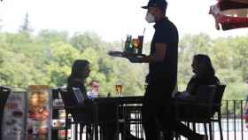 Un camarero protegido con mascarilla atiende a una mesa de una terrazas / Europa Press