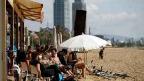 Algunas personas disfrutan de las temperaturas veraniegas en un chiringuito de una playa de Barcelona / EFE