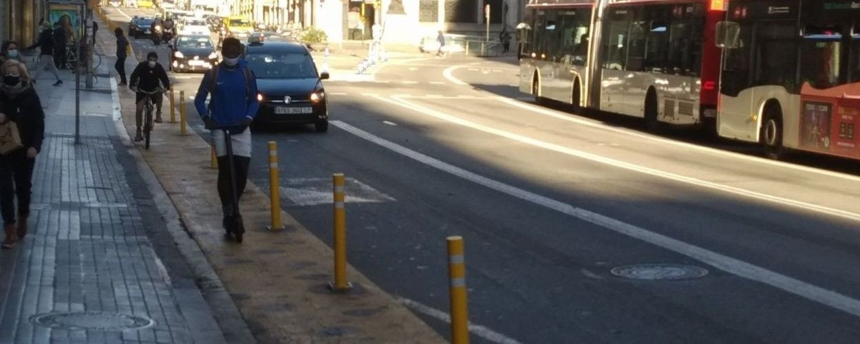 Un patinete y una bici en el carril peatonal de vía Laietana de Barcelona con separadores para proteger al peatón / MA - JORDI SUBIRANA