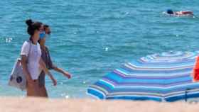 Dos chicas en la playa y con mascarilla en un día de calor / EFE