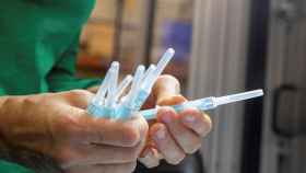 Una operaria inspecciona unas muestras de la jeringuilla para administrar la vacuna contra el coronavirus / EFE