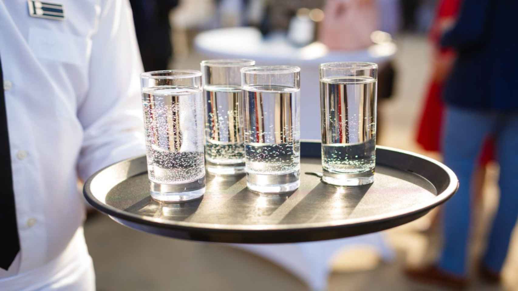 Un camarero lleva cuatro vasos de agua en un bar / ARCHIVO