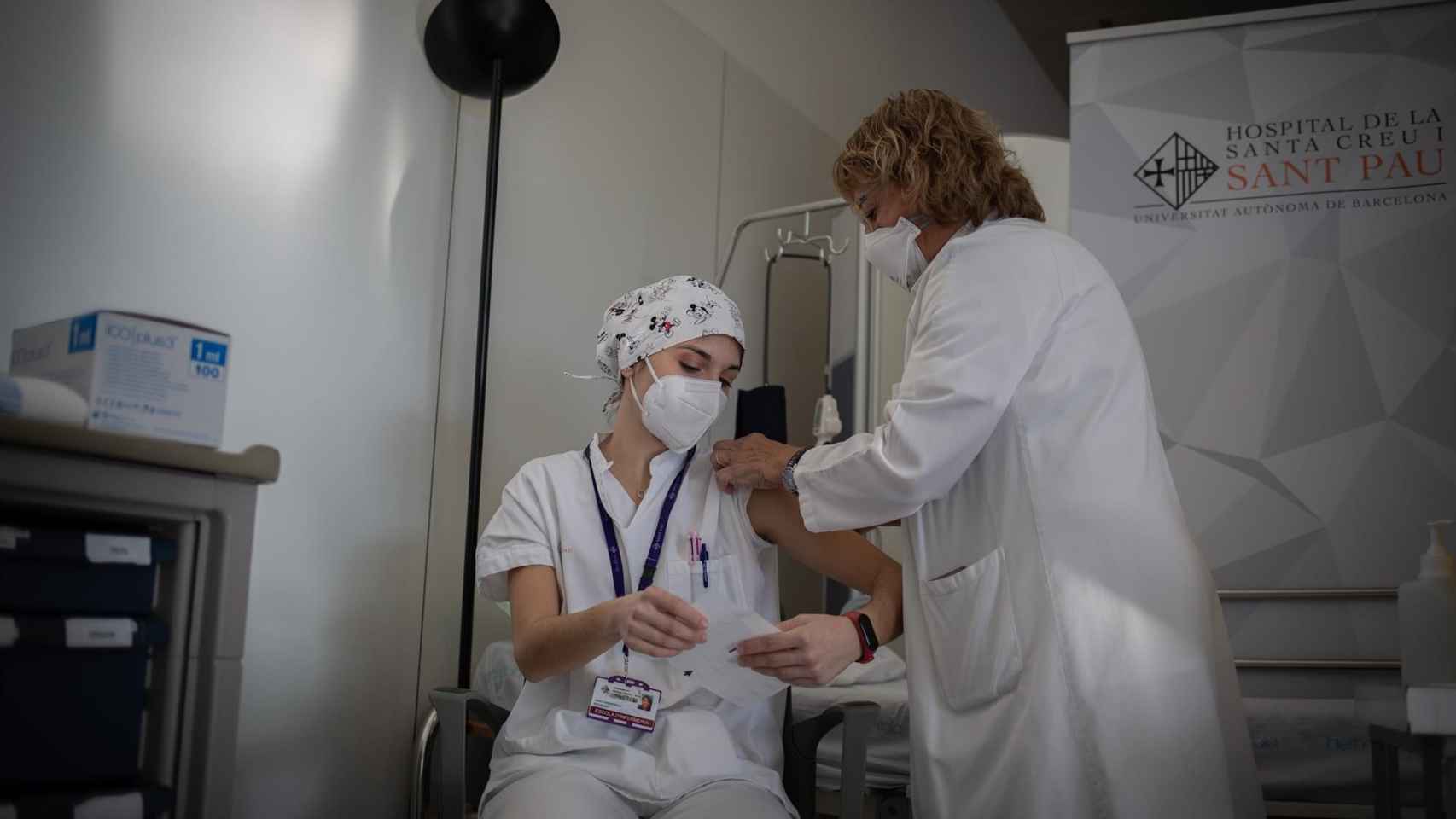 Una enfermera vacuna a un profesional sanitario con la vacuna de Pfizer-BioNtech contra el COVID-19 en el Hospital de la Santa Creu i Sant Pau de Barcelona / David Zorrakino
