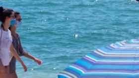 Dos chicas en la playa y con mascarilla en un día de calor en Barcelona / EFE