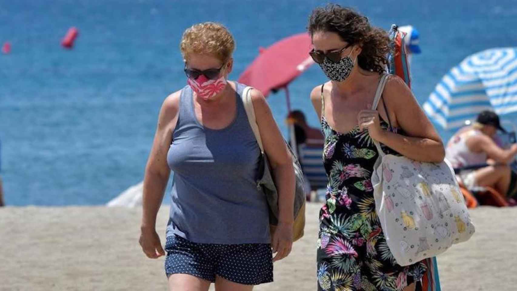 Dos mujeres con mascarilla en la playa en un día de mucho calor / EFE