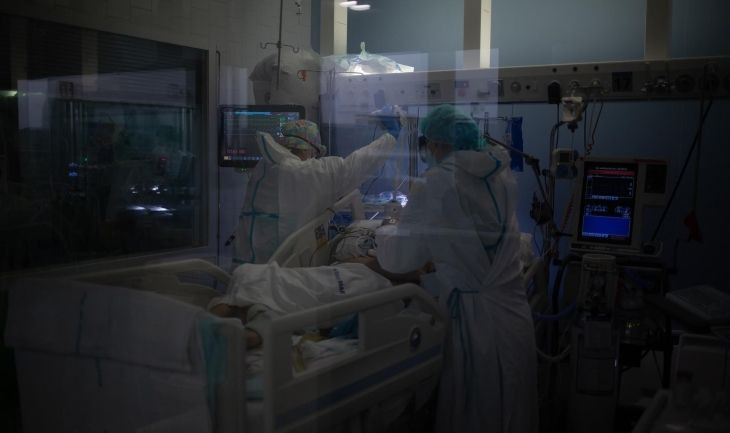 Trabajadores sanitarios protegidos atienden a un paciente en la Unidad de Cuidados Intensivos / David Zorrakino - Europa Press