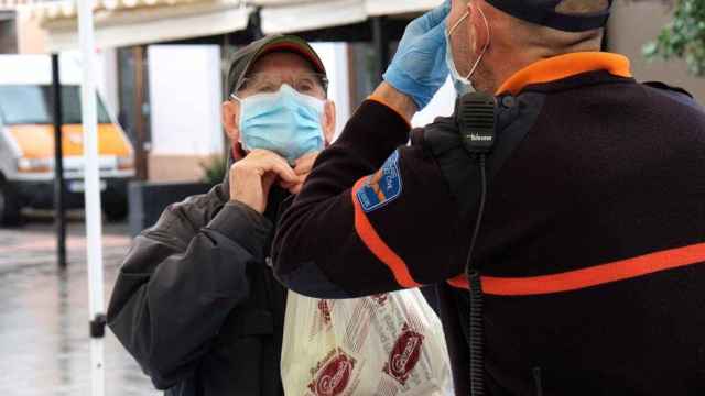 Un hombre recibe las indicaciones de cómo colocarse la mascarilla / Isaac Buj - Europa Press