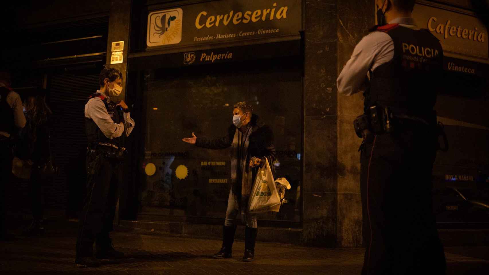 Varios mossos d'Esquadra paran a una persona durante un control durante el toque de queda