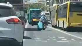 Un pasajero de una motocicleta arrastra una maleta por el centro de Barcelona / INSTAGRAM