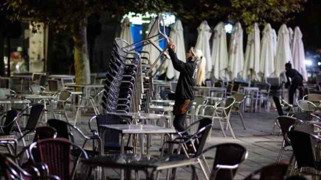 Una camarera recoge la terraza de un bar momentos antes del inicio del toque de queda / EFE - Nacho Gallego