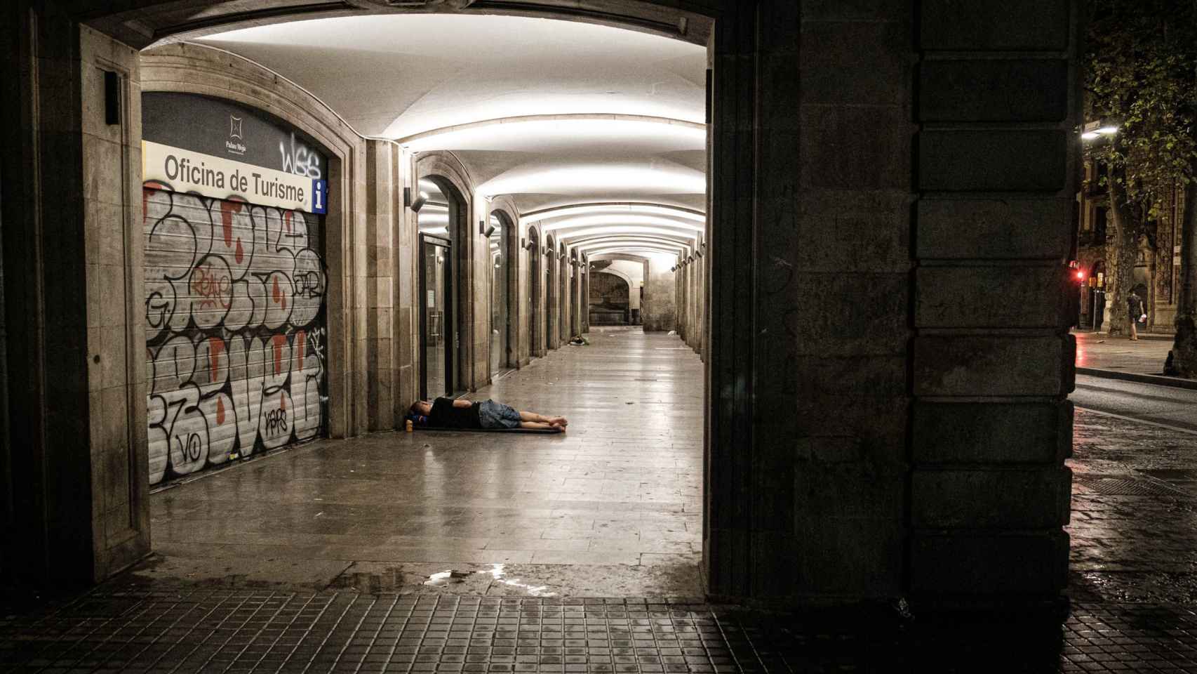 Una persona sintecho durmiendo en los arcos próximos a la calle de la Portaferrissa / PABLO MIRANZO - MA
