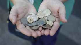 Una persona muestra un puñado de monedas de las antiguas pesetas mientras hace cola para entrar en el Banco de España / EUROPA PRESS