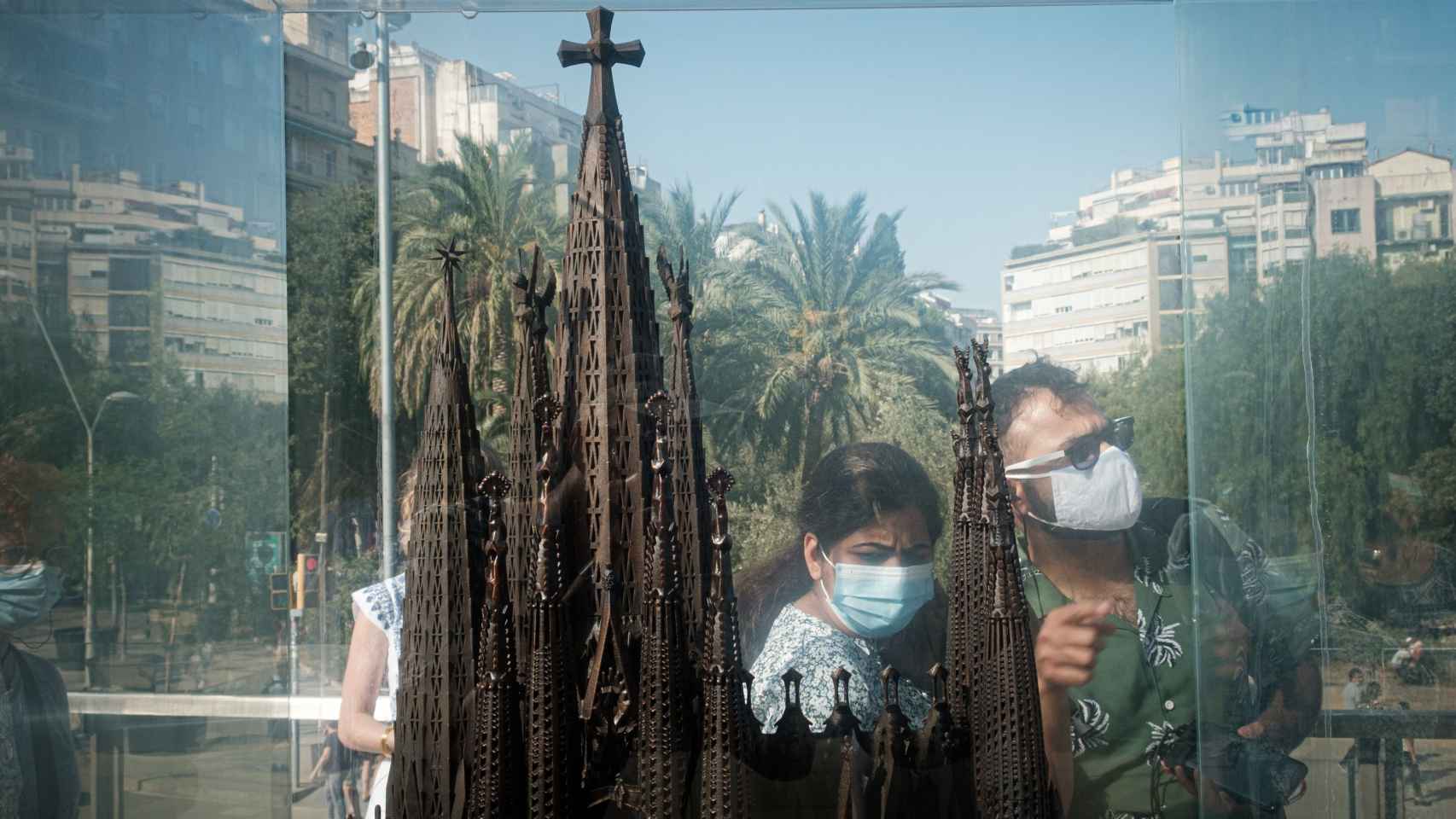 Dos turistas con mascarilla se reflejan en uno de los expositores de las maquetas de la Sagrada Família / PABLO MIRANZO - MA