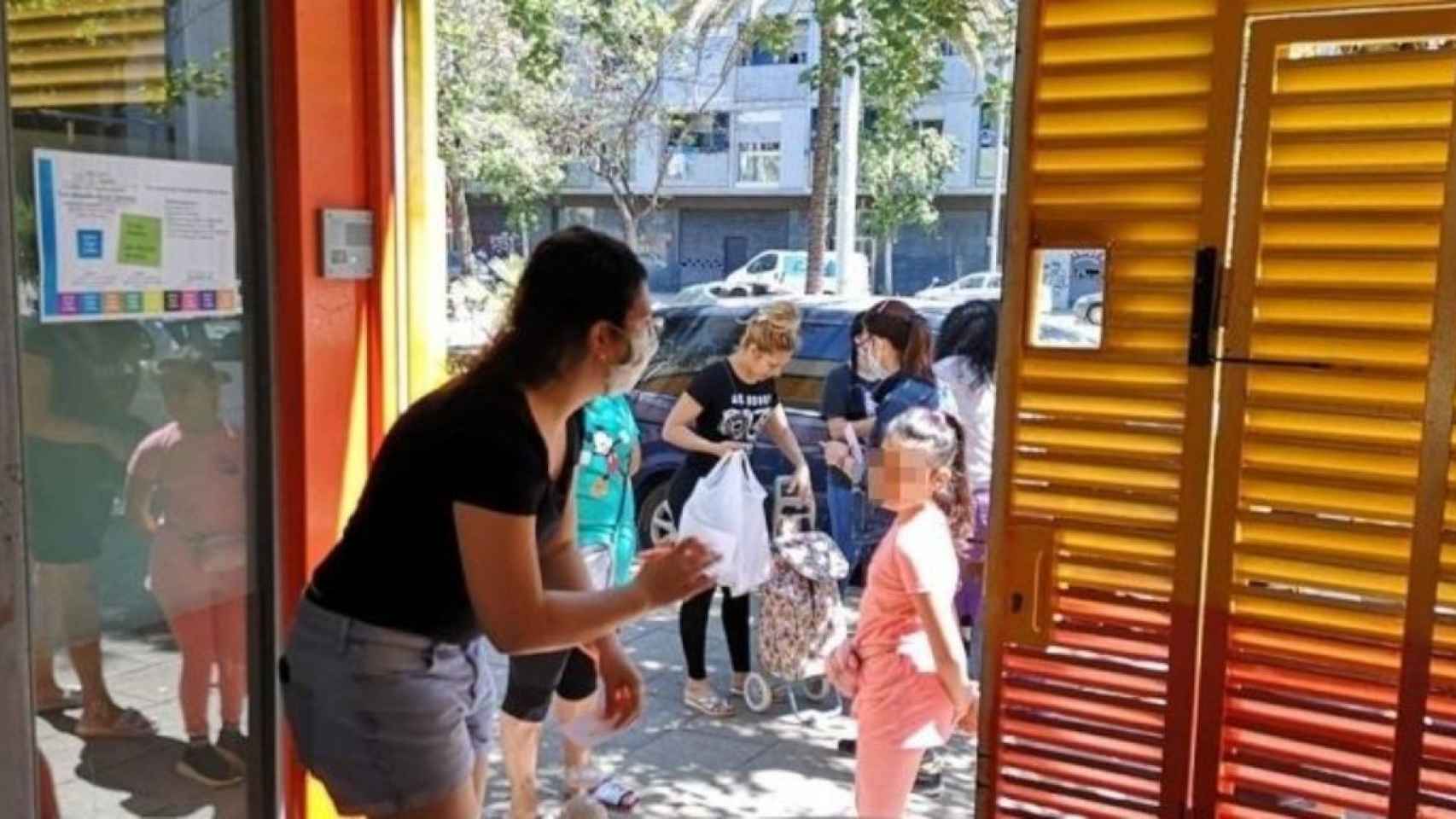 Una educadora habla con una niña en la puerta de la escuela de La Mina en marzo de 2020 / GUILLEM ANDRÉS