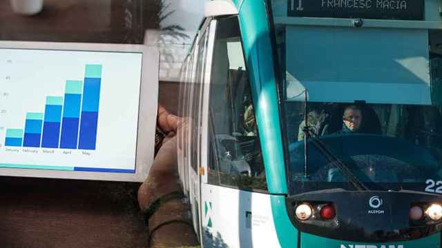 Montaje de una persona consultando una tablet y un tranvía que circula por la Diagonal / FOTOMONTAJE